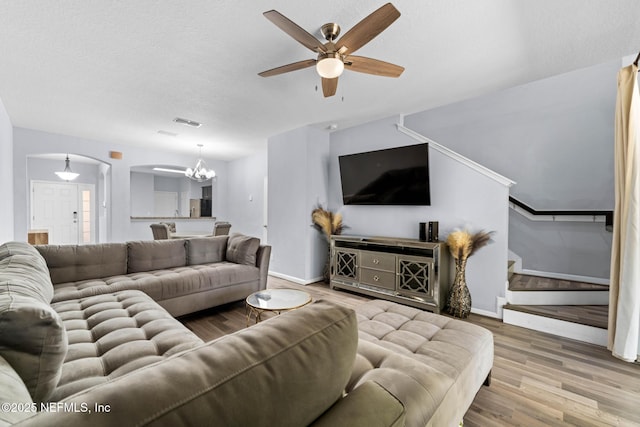 living area with visible vents, wood finished floors, arched walkways, baseboards, and stairs