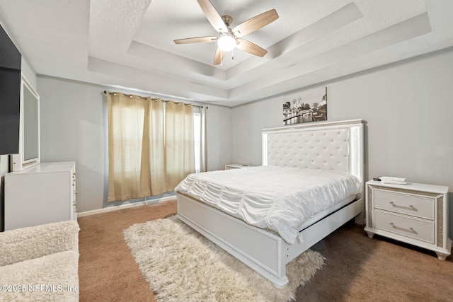 bedroom with carpet flooring, a raised ceiling, and a ceiling fan