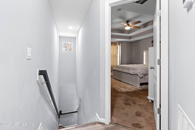 corridor featuring a raised ceiling, carpet flooring, and visible vents