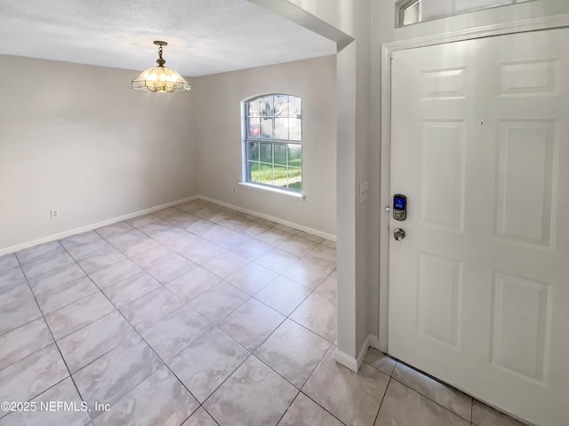 entrance foyer with a chandelier, light tile patterned floors, and baseboards