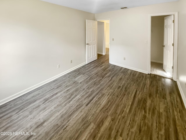 unfurnished bedroom featuring visible vents, baseboards, and dark wood-style floors