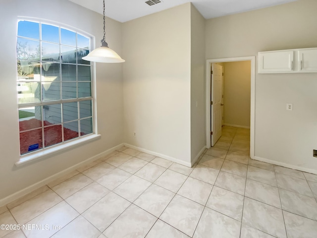 empty room featuring light tile patterned floors, visible vents, and baseboards