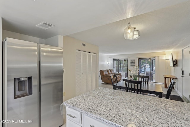 5400 La Moya Ave Unit 16, Jacksonville, FL 32210 - kitchen featuring light stone counters, visible vents, stainless steel fridge, and white cabinets