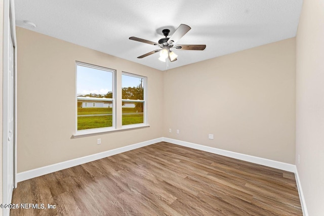 unfurnished room featuring a textured ceiling, wood finished floors, baseboards, and ceiling fan