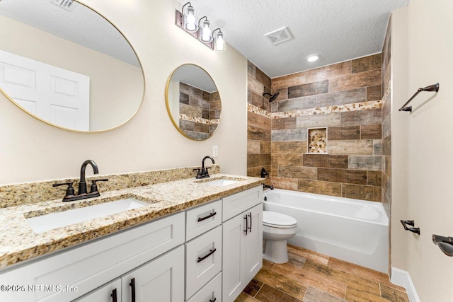 full bath featuring a textured ceiling, wood tiled floor, visible vents, and a sink