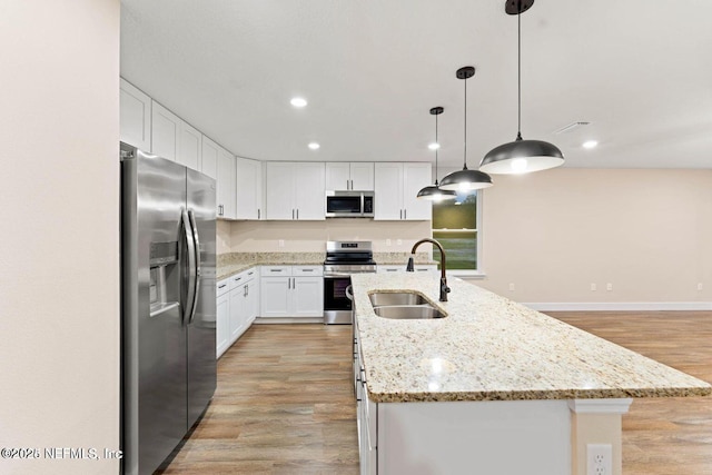 kitchen with a center island with sink, appliances with stainless steel finishes, light wood-type flooring, and a sink