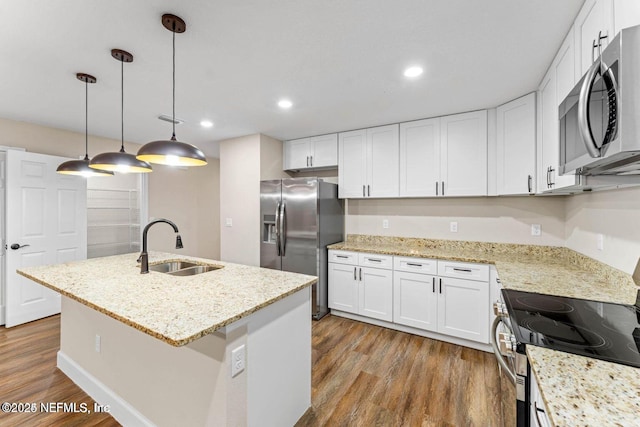 kitchen featuring an island with sink, stainless steel appliances, wood finished floors, white cabinetry, and a sink