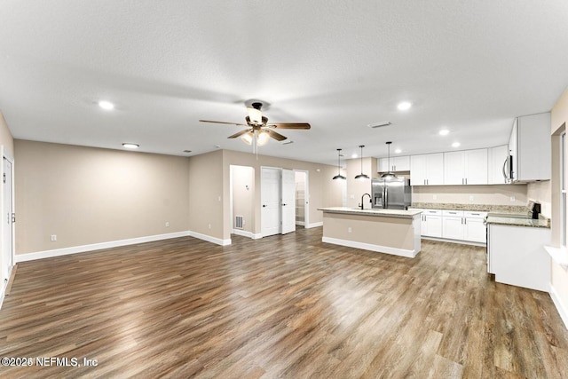 kitchen with dark wood finished floors, a center island with sink, open floor plan, and stainless steel refrigerator with ice dispenser