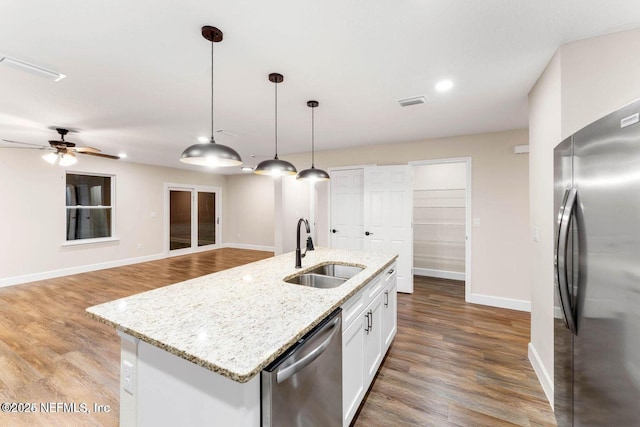 kitchen with a sink, appliances with stainless steel finishes, wood finished floors, and pendant lighting