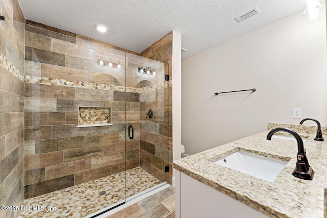 bathroom with a sink, visible vents, a textured ceiling, and a stall shower