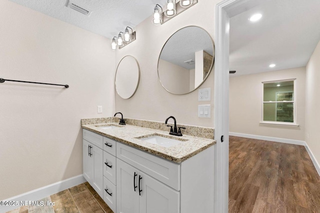 bathroom featuring a sink, visible vents, baseboards, and wood finished floors