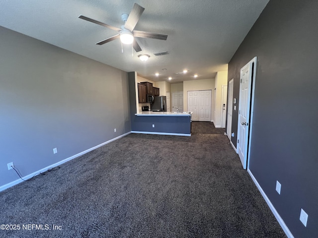 unfurnished living room with visible vents, dark carpet, a textured ceiling, and baseboards