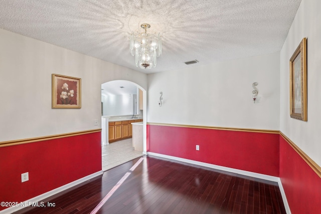 2721 Ridge Haven Dr, Green Cove Springs, FL 32043 - empty room featuring a textured ceiling, baseboards, arched walkways, an inviting chandelier, and wood-type flooring