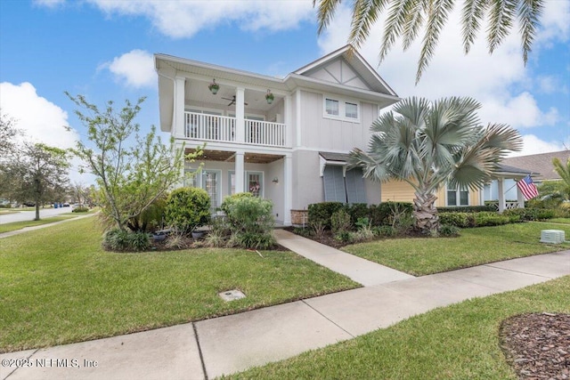 view of front of home featuring a balcony, board and batten siding, a ceiling fan, and a front yard