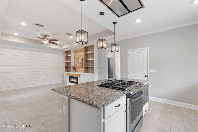 kitchen featuring visible vents, baseboards, a glass covered fireplace, gas stove, and a raised ceiling