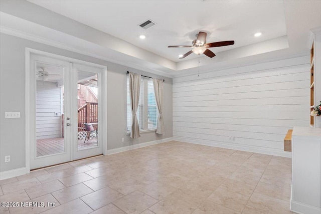 unfurnished room with baseboards, visible vents, a ceiling fan, and a tray ceiling