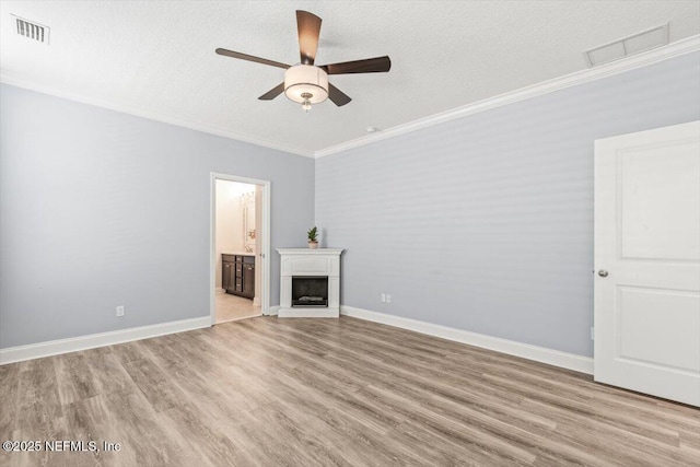 unfurnished living room featuring visible vents, light wood-style flooring, a fireplace, and crown molding