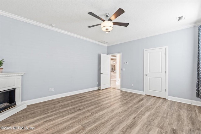 unfurnished living room featuring crown molding, a fireplace with raised hearth, visible vents, and light wood-type flooring