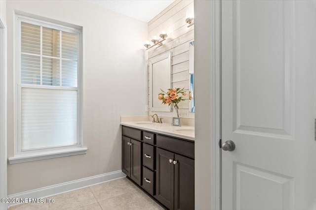 full bathroom featuring double vanity, baseboards, tile patterned floors, and a sink