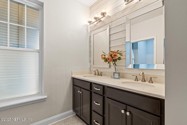 bathroom with a sink, baseboards, and double vanity