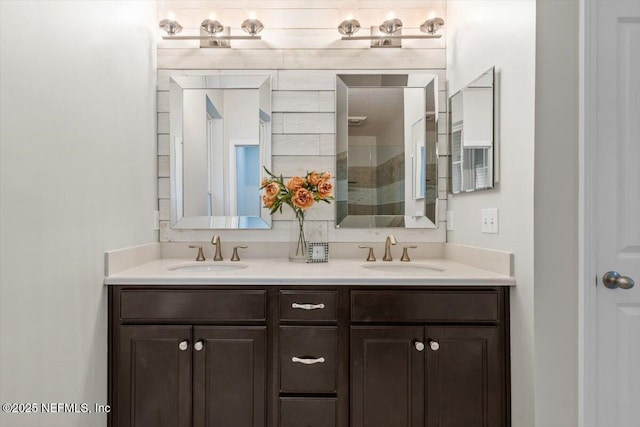 bathroom with double vanity, tiled shower, and a sink