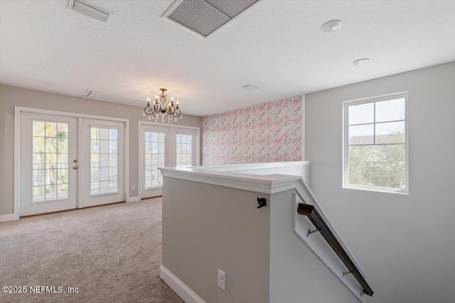 corridor featuring visible vents, french doors, and a textured ceiling