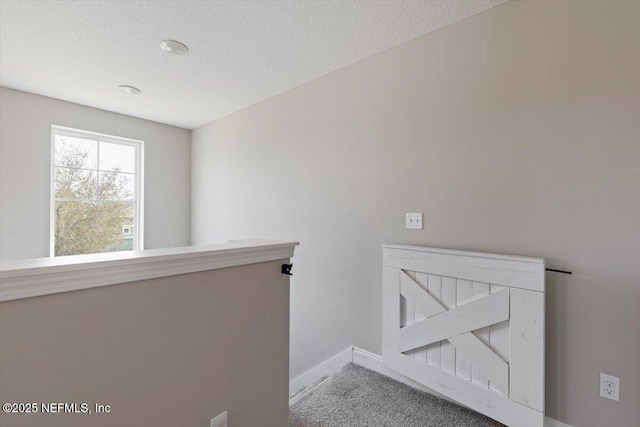 interior space with an upstairs landing, carpet flooring, a textured ceiling, and baseboards