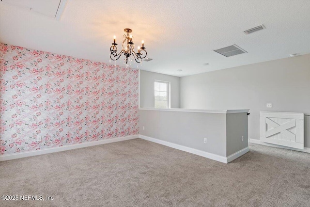 carpeted empty room with an inviting chandelier, baseboards, visible vents, and a textured ceiling