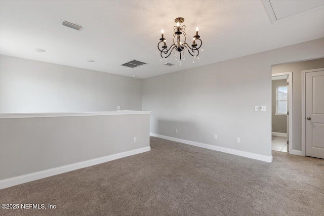 spare room featuring carpet, visible vents, a chandelier, and baseboards