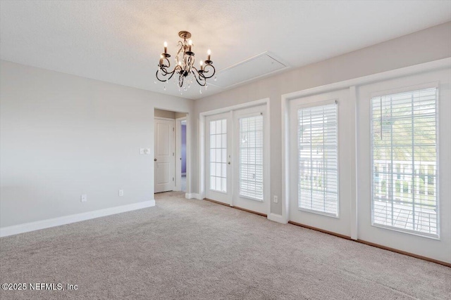 carpeted empty room featuring attic access, baseboards, and a textured ceiling