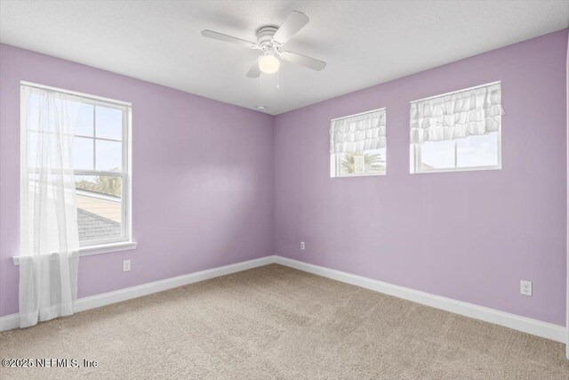 empty room with carpet flooring, a ceiling fan, and baseboards