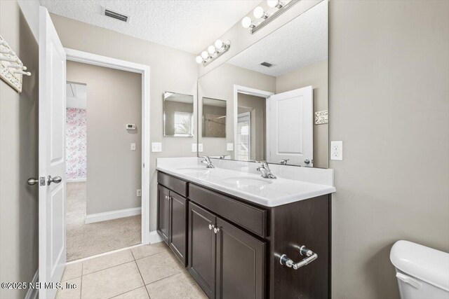 bathroom with tile patterned flooring, toilet, a textured ceiling, and a sink