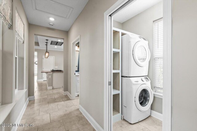 laundry area with laundry area, baseboards, and stacked washer and dryer