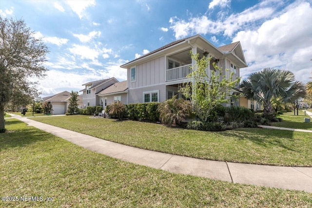 view of front of house featuring a front yard, a balcony, and board and batten siding