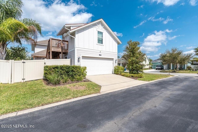 view of front of property with board and batten siding, fence, a garage, driveway, and a gate