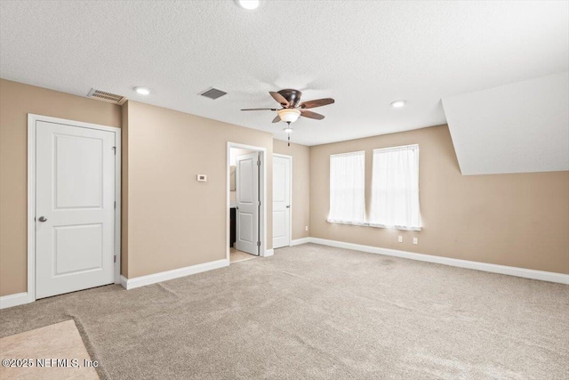 unfurnished bedroom featuring visible vents, a textured ceiling, baseboards, and carpet