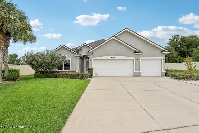 ranch-style house featuring a front lawn, fence, stucco siding, driveway, and an attached garage