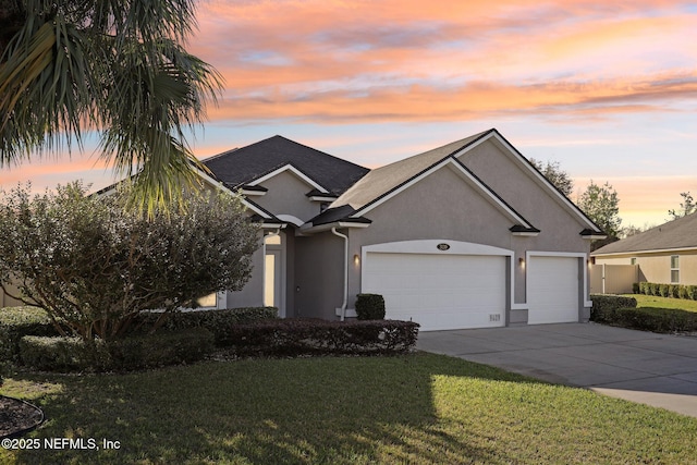 view of front of house featuring a shingled roof, concrete driveway, stucco siding, a lawn, and an attached garage