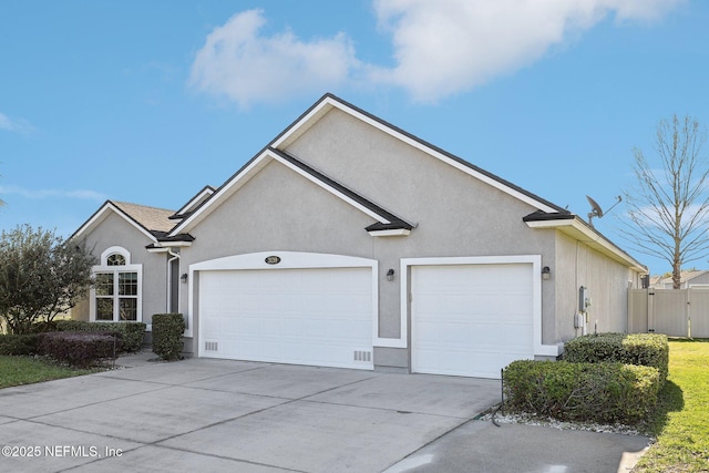 ranch-style house featuring a garage, fence, concrete driveway, and stucco siding