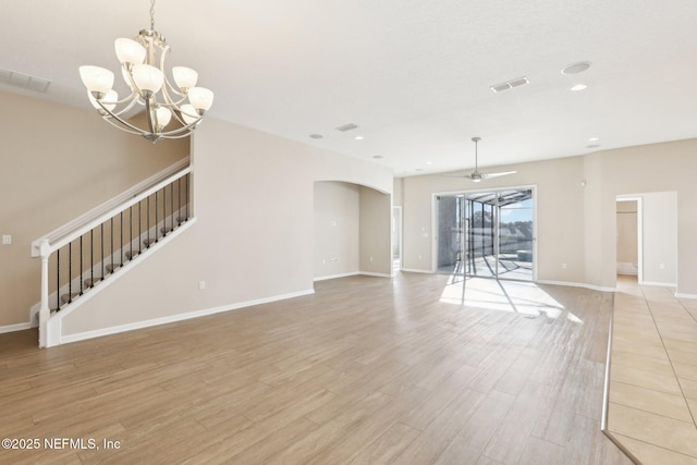 unfurnished living room featuring light wood-type flooring, visible vents, baseboards, and ceiling fan with notable chandelier