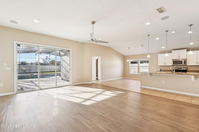 unfurnished living room featuring a ceiling fan, baseboards, visible vents, lofted ceiling, and light wood-type flooring