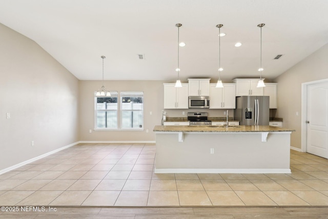 kitchen with a center island with sink, a kitchen breakfast bar, appliances with stainless steel finishes, white cabinets, and lofted ceiling