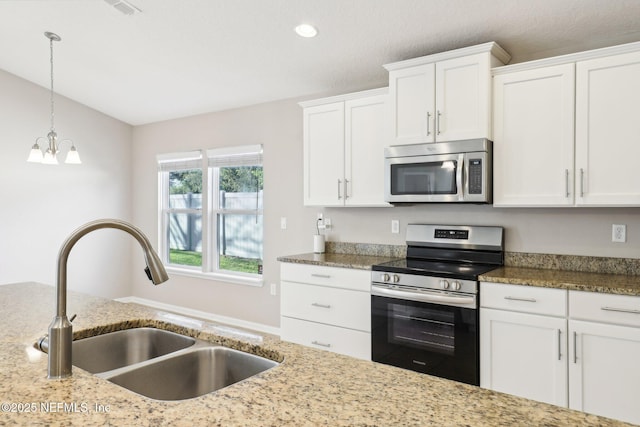 kitchen with a sink, stainless steel appliances, light stone counters, and white cabinetry