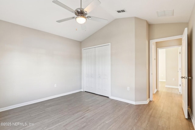 unfurnished bedroom featuring a closet, visible vents, light wood-type flooring, and vaulted ceiling