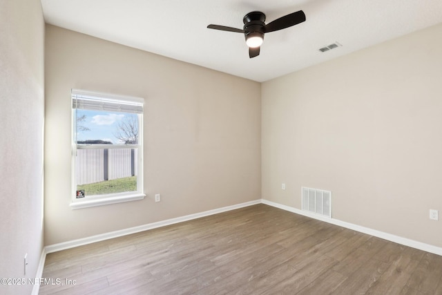 spare room featuring baseboards, wood finished floors, visible vents, and ceiling fan