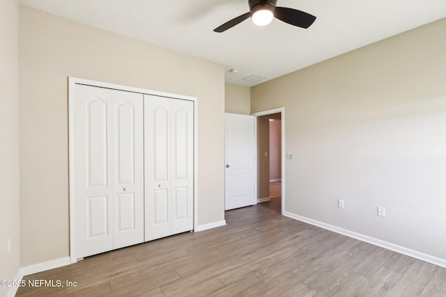 unfurnished bedroom featuring ceiling fan, a closet, baseboards, and light wood-style flooring