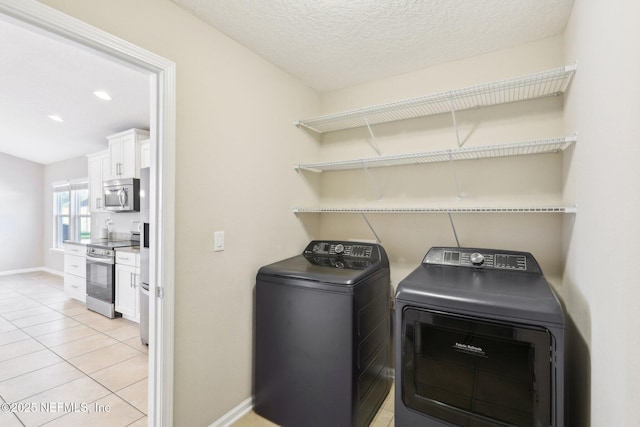 laundry room featuring independent washer and dryer, a textured ceiling, light tile patterned flooring, baseboards, and laundry area