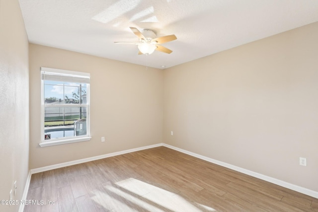 unfurnished room featuring ceiling fan, baseboards, a textured ceiling, and wood finished floors