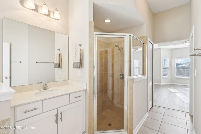 full bathroom featuring vanity, baseboards, a stall shower, ceiling fan, and tile patterned floors