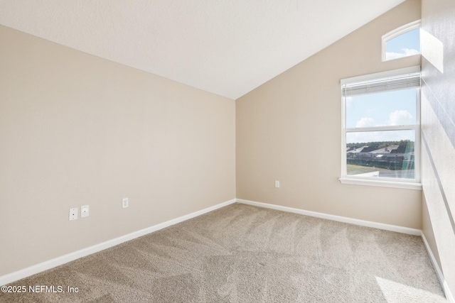 empty room featuring vaulted ceiling, baseboards, and carpet floors